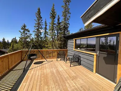 a wooden deck with two chairs on a house at Modern Cozy Cabin Near Langsua National Park in Heggenes