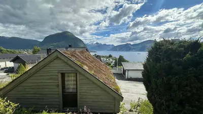 a small house with a view of a lake and mountains at Cozy Cabin in Volda