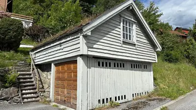 a small white building with a wooden garage at Cozy Cabin in Volda