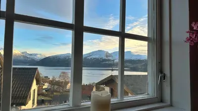 a window with a view of a lake and mountains at Cozy Cabin in Volda