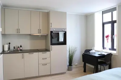 a kitchen with white cabinets and a table in a room at One-bedroom apartment close to NTNU and St Olavs in Trondheim