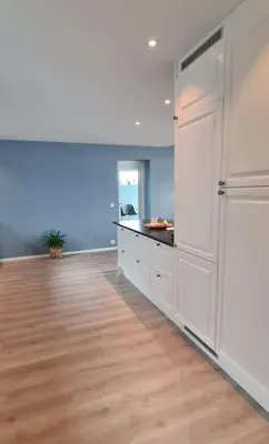 a large kitchen with white cabinets and a wooden floor at Villa with a view in Ålesund