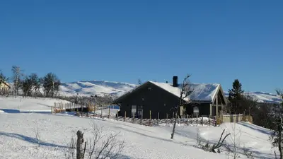 a house in a snow covered field with a building at NEUE Fjellhytte in Etnedal