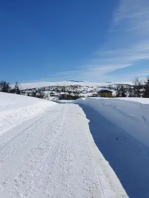 a snow covered road with a house in the distance at NEUE Fjellhytte in Etnedal