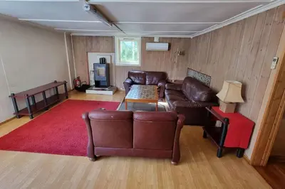 a living room with leather furniture and a red rug at House in Austevoll in Austevoll
