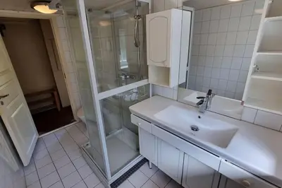 a white bathroom with a sink and a shower at House in Austevoll in Austevoll