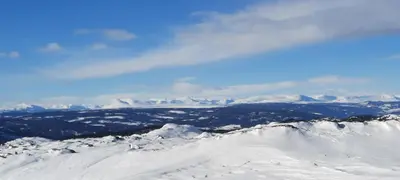 a view of the snow covered mountains from the top of a mountain at HYTTEEVENTYR I VALDRES MED JACUZZI, 5 soverom, alpinbakke og skiløyper like ved! in Aurdal