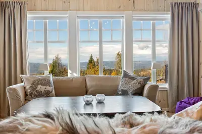 a living room with a couch and a table in front of a window at HYTTEEVENTYR I VALDRES MED JACUZZI, 5 soverom, alpinbakke og skiløyper like ved! in Aurdal