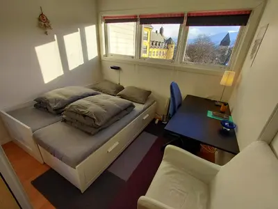 a small bedroom with a bed and a desk at Private room in central homestay apartment with sea view in Ålesund