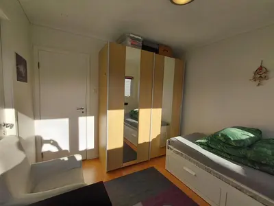 a bathroom with a sink and a bed and a mirror at Private room in central homestay apartment with sea view in Ålesund