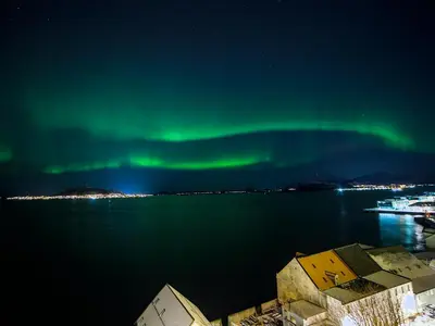 an aurora in the sky over a body of water at Private room in central homestay apartment with sea view in Ålesund