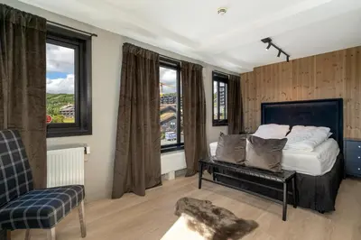 a bedroom with a bed and two windows at Stølstunets toppetasje in Beitostøl
