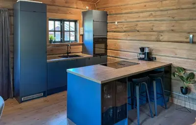 a kitchen with wooden walls and a blue island with bar stools at Lovely Home In Uvdal With Sauna in Uvdal