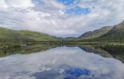 a reflection of the mountains in a lake at Stunning Home In Rjukan With Sauna in Rjukan
