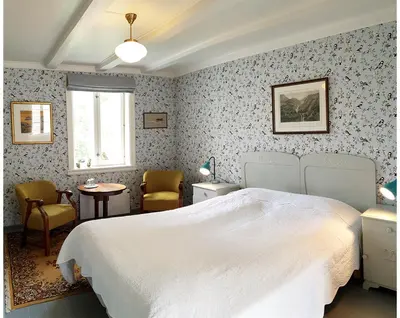 a bedroom with a white bed and a table and chairs at Sanden pensjonat in Lærdalsøyri