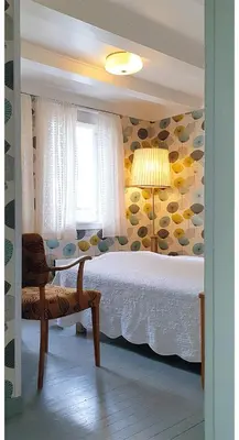 a bedroom with a bed and a chair and a lamp at Sanden pensjonat in Lærdalsøyri