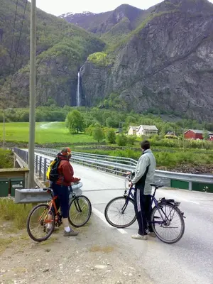 two people on bikes on a bridge with a waterfall at Sanden pensjonat in Lærdalsøyri