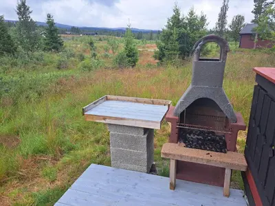 an outdoor grill with a wooden table and a wooden table at Trollbu by Norgesbooking - cabin at Golsfjellet in Sanderstølen
