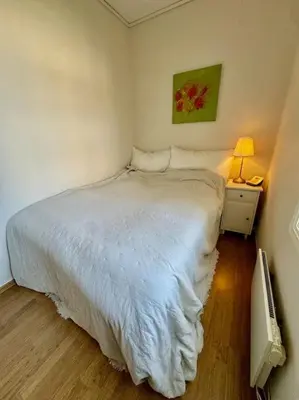 a bedroom with a white bed and a night stand with a lamp at Leilighet i herskapelig villa in Trondheim