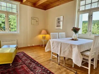 a dining room with a table and chairs and windows at Leilighet i herskapelig villa in Trondheim