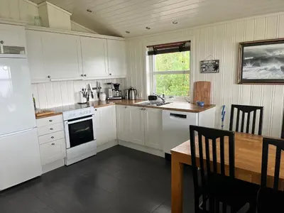 a kitchen with white cabinets and a wooden table and a tableablish at Hytte i Lysøysund med 4 soverom, Ørland in Lysøysund