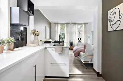 a kitchen with white cabinets and a bed in a room at Koselig leilighet ved Solsiden in Trondheim