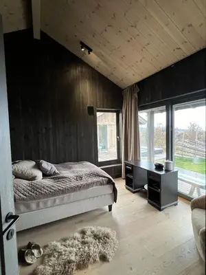 a bedroom with a bed and a desk and windows at Spacious, exclusive and modern cabin in Geilo in Geilo