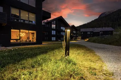 a building with a pole in the grass next to a road at Exclusive Ski In-Out apartment in Hemsedal next to Fyri Resort in Hemsedal
