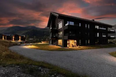 a building on a hill with mountains in the background at Exclusive Ski In-Out apartment in Hemsedal next to Fyri Resort in Hemsedal
