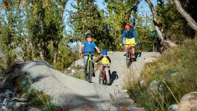 a man and two children riding bikes on a trail at Exclusive Ski In-Out apartment in Hemsedal next to Fyri Resort in Hemsedal