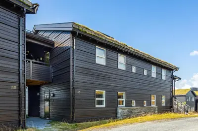 a black house with a balcony on the side of it at Nydelig utsikt, ski in out, 3 soverom in Aurdal