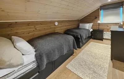two beds in a room with wooden walls at 5 Bedroom Nice Home In Edland in Vågsli