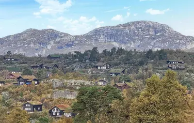 a group of houses on a hill with mountains in the background at 5 Bedroom Nice Home In Edland in Vågsli