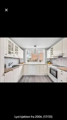 a large kitchen with white cabinets and a window at Koselig rekkehus med tre soverom in Trondheim