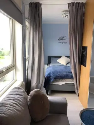 a bedroom with a bed and a couch and a window at Koselig rekkehus med tre soverom in Trondheim
