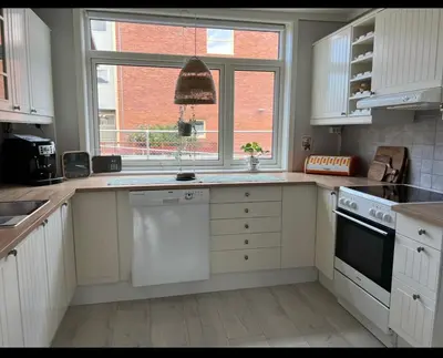 a kitchen with white cabinets and a window at Koselig rekkehus med tre soverom in Trondheim