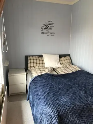 a bedroom with a bed with a blue blanket at Koselig rekkehus med tre soverom in Trondheim