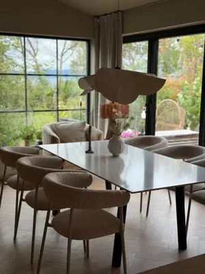 a table and chairs in a living room with windows at Vakreste plass og beliggenhet! in Trondheim