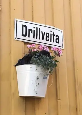 a flower pot hanging on a wall with a sign at Koselig studioleilighet i sentrum in Trondheim