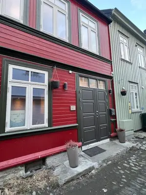 a red and green house with a door and windows at Koselig studioleilighet i sentrum in Trondheim