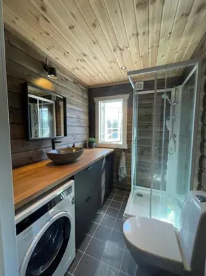 a bathroom with a shower and a washing machine at Delikat tømmerhytte på Blefjell in Flesberg
