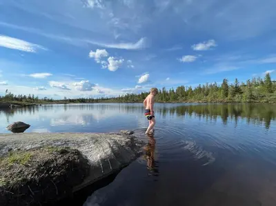 a man standing in the water in a lake at Delikat tømmerhytte på Blefjell in Flesberg