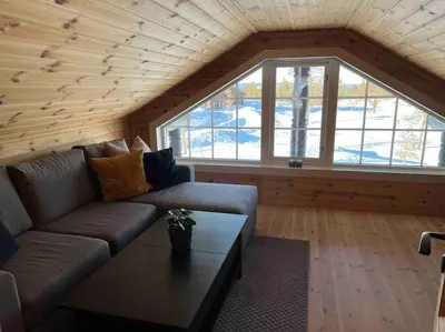 a living room with a couch and a table at Delikat tømmerhytte på Blefjell in Flesberg