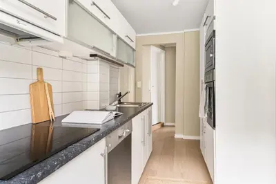 a kitchen with white cabinets and a black counter top at Sentral leilighet med parkering og peis in Bergen