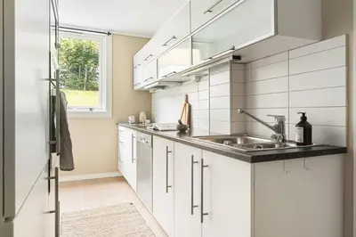 a kitchen with white cabinets and a sink at Sentral leilighet med parkering og peis in Bergen