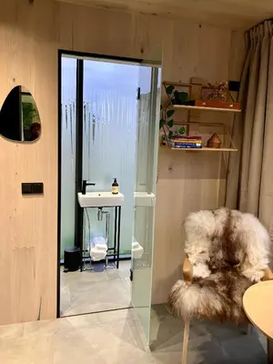 a room with a glass door and a furry chair at Glimre Romsdal - Eksklusivt speilhus ved Åndalsnes in Isfjorden