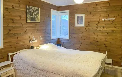 a bedroom with a bed and a wooden wall at Beautiful Home In Skodje in Vatne
