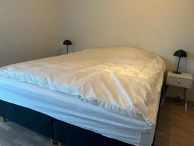 a bed with white sheets on it in a bedroom at Heimdal Sentrum in Heimdal