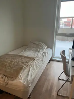 a bed in a room with a desk and a window at Heimdal Sentrum in Heimdal