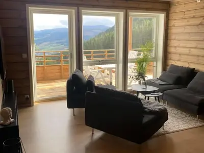 a living room with a couch and a large window at Oppgradert leilighet i Tråstølen in Skulestadmo